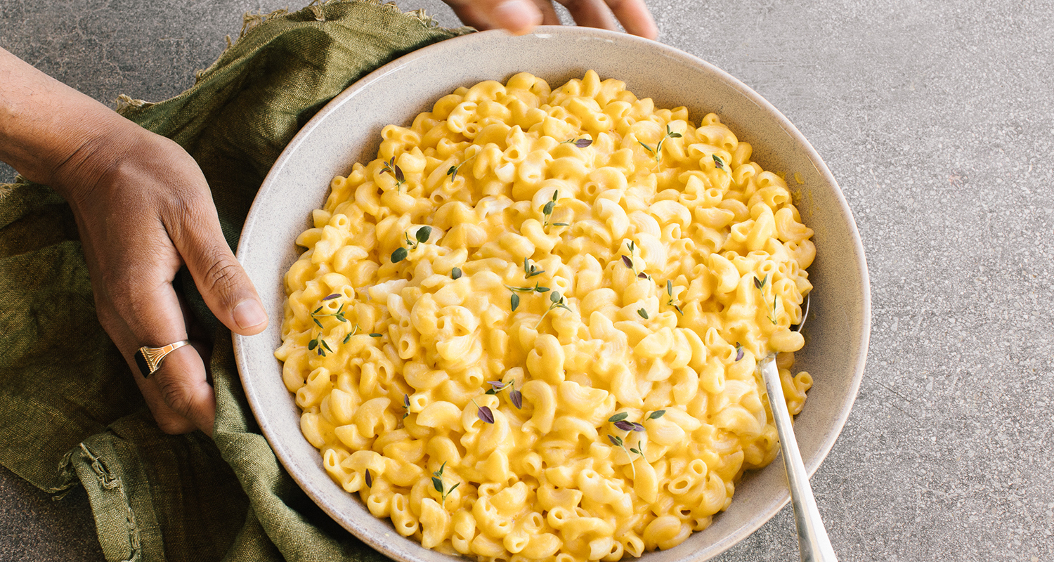 hands holding a large bowl of mac and cheese